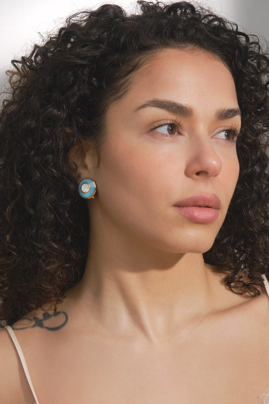Close-up of a woman with curly hair wearing a blue earring.