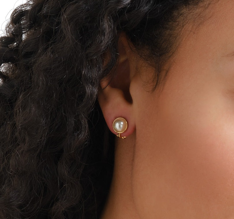 Close-up of a person wearing a pearl earring with dark hair.