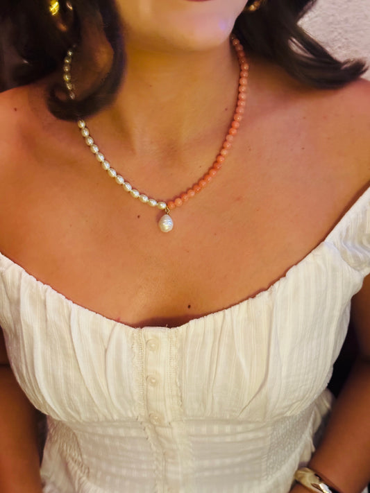 Close-up of a person wearing a pearl necklace with a white dress.