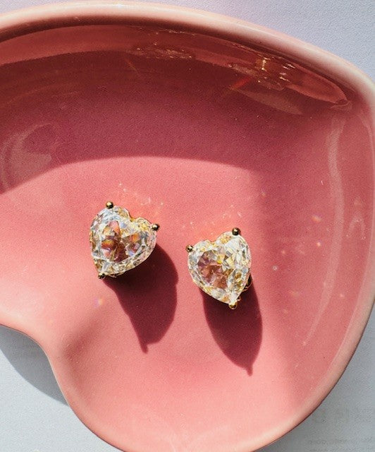 Heart-shaped diamond earrings on a pink dish