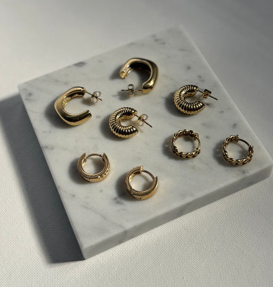 Gold hoop earrings displayed on a marble surface