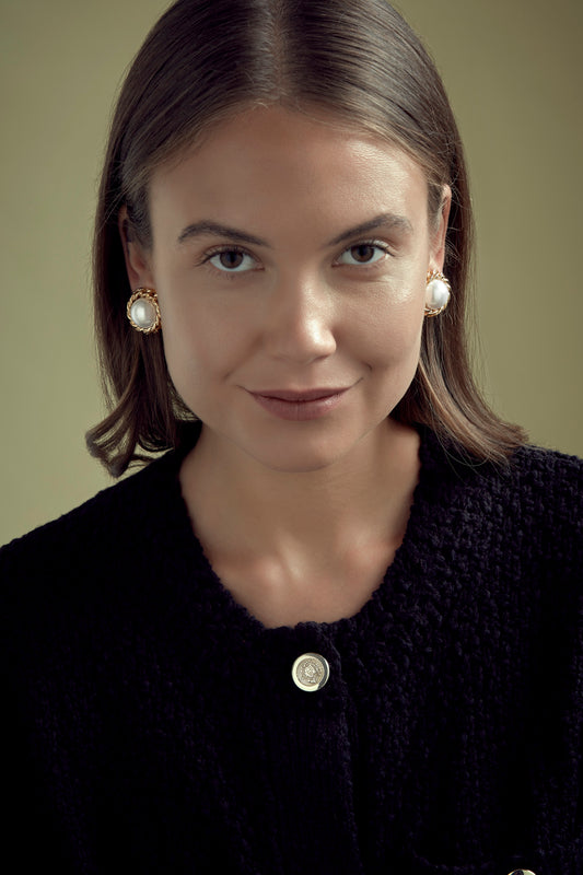 Model wearing large pearl and gold clip on earrings