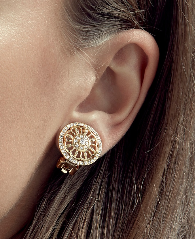 Close-up of a gold earring with intricate design worn by a person.
