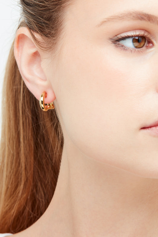 A close up model shot of gold clip on hoop earrings