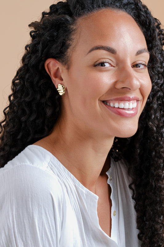 A model wearing Gold ripple clip on earrings