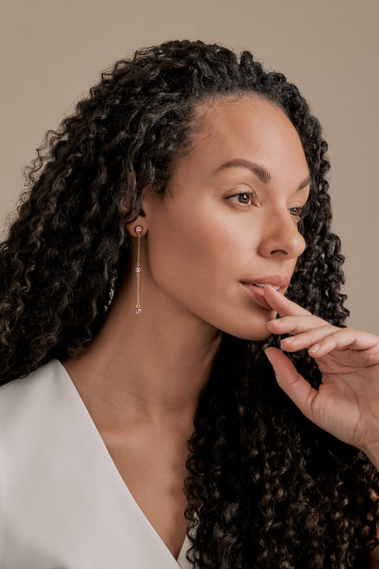 A model wearing gold and pink crystal earrings