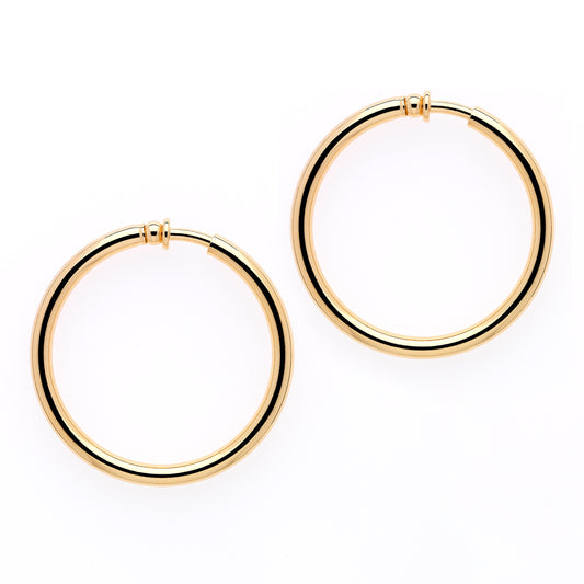 A pair of large gold hoop clip earrings on a white background.