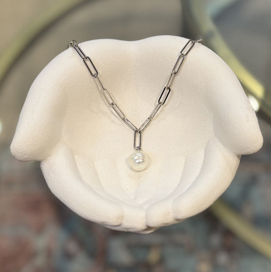 Silver necklace with a pearl pendant on a white stand