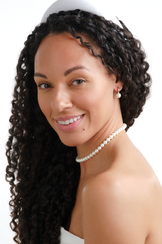 A bridal shot of a model wearing platinum and pearl earrings