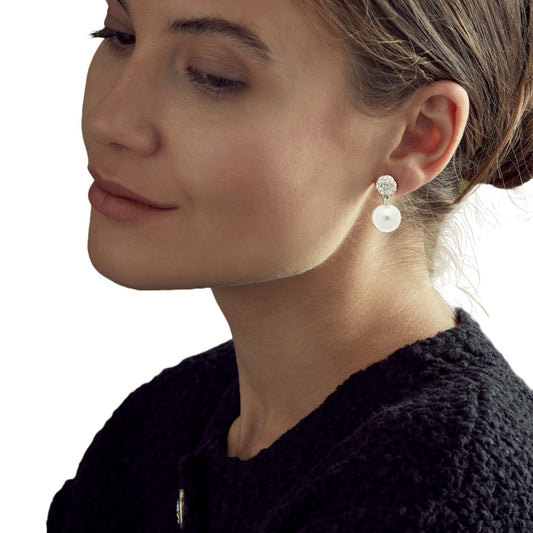 Close-up of a woman wearing pearl earrings with a neutral background