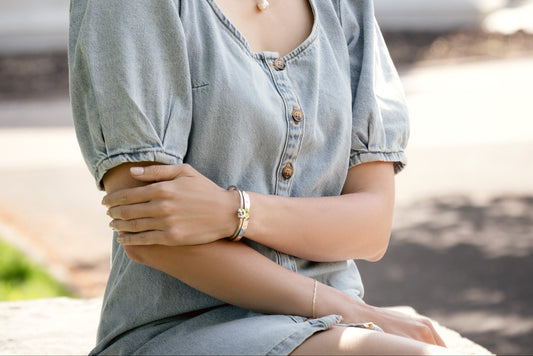 Person wearing a light blue denim shirt with a blurred background and silver jewellery