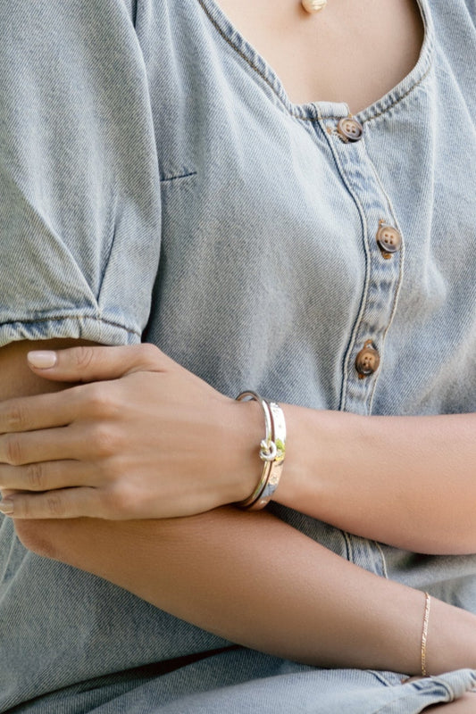 A model wearing a silver love knot bangle