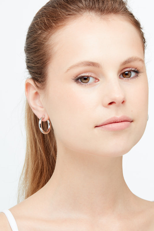 A model wearing silver clip on hoop earrings