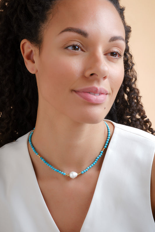 A model wearing turquoise necklace and a pearl centre