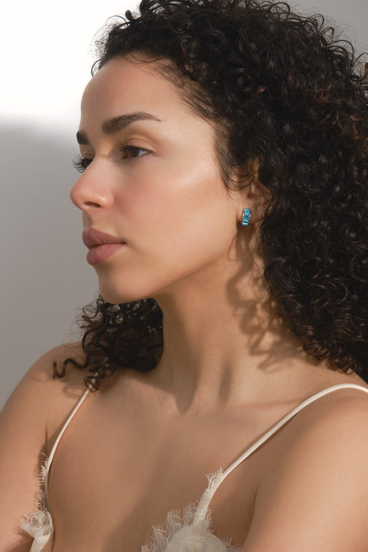 Woman wearing a delicate lace top with a neutral background with Aqua clip earrings