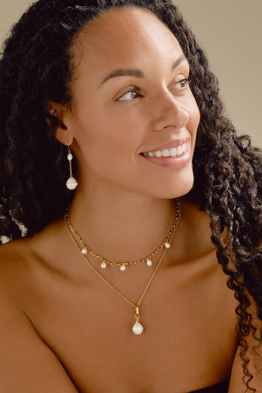 Woman wearing pearl jewelry with a neutral background