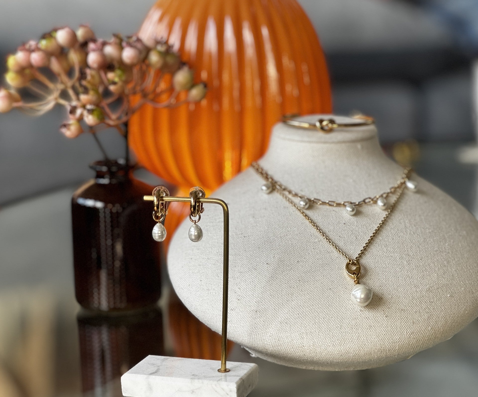 Jewelry display with necklaces on a mannequin bust and decorative items in the background.