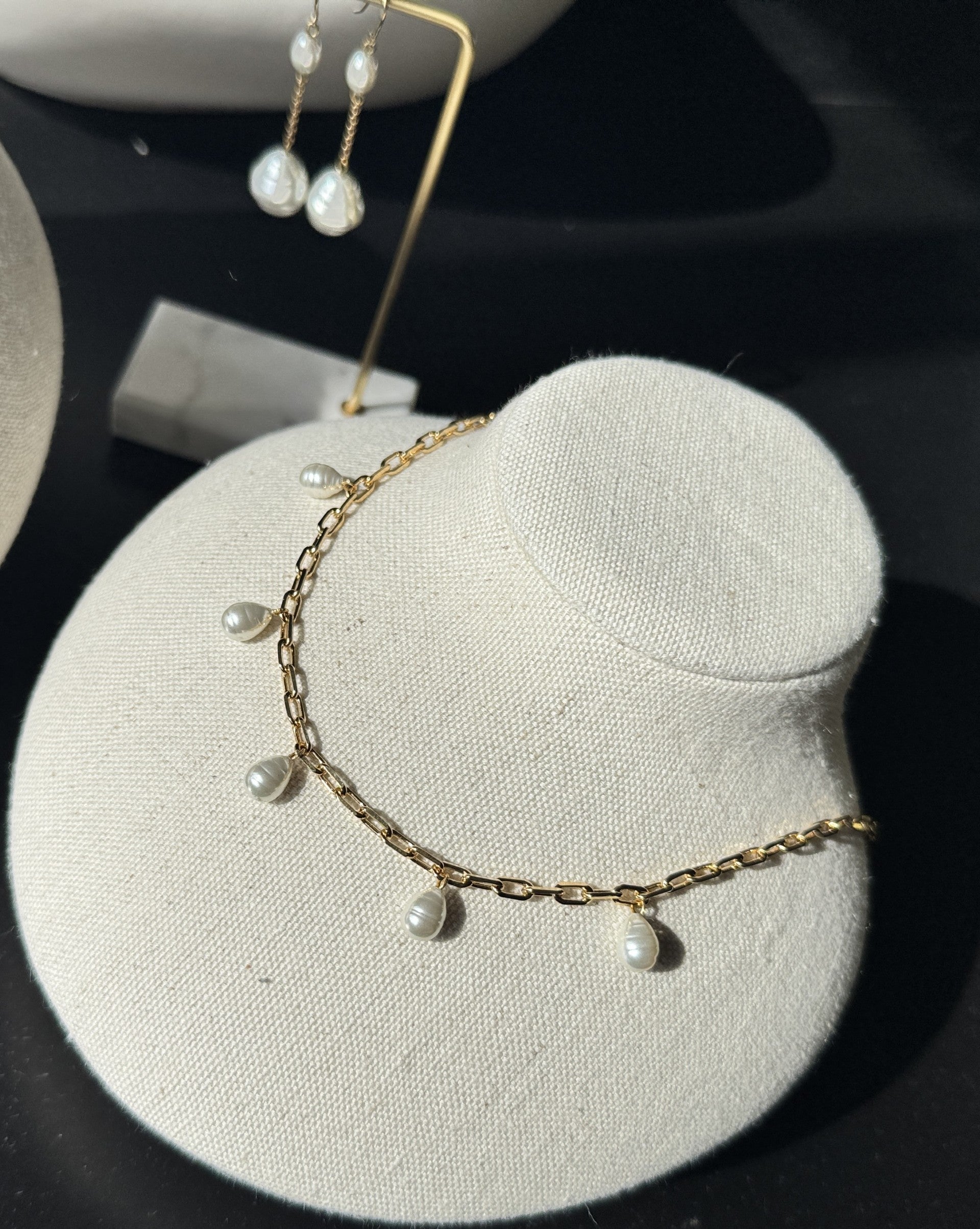 Gold necklace with pearls on a gray jewelry display