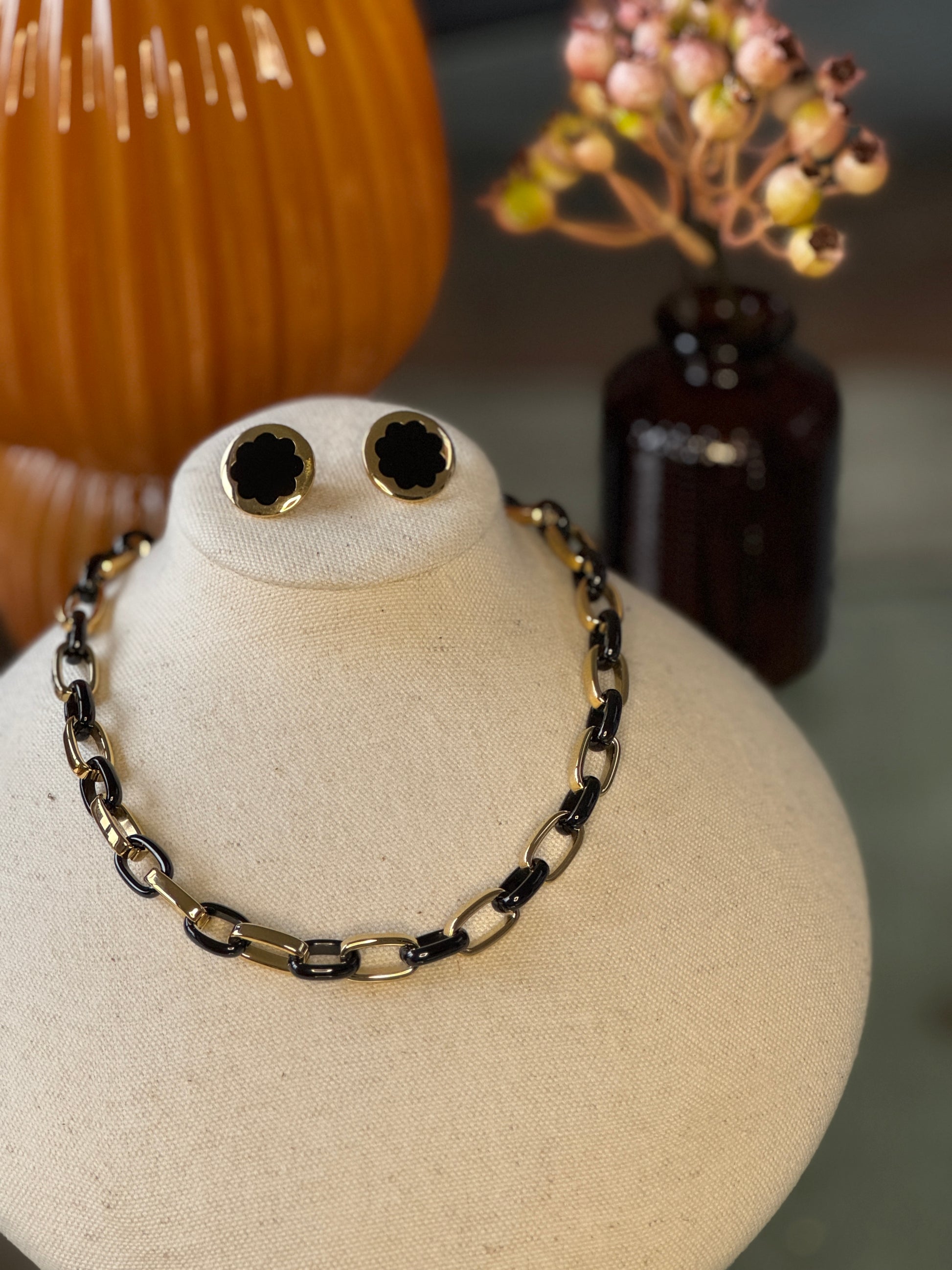 Necklace and earrings on a mannequin bust with decorative background