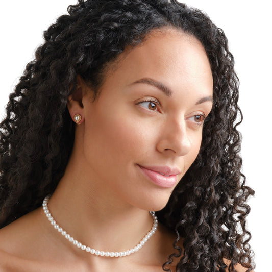 Woman with curly hair wearing a pearl necklace on a white background