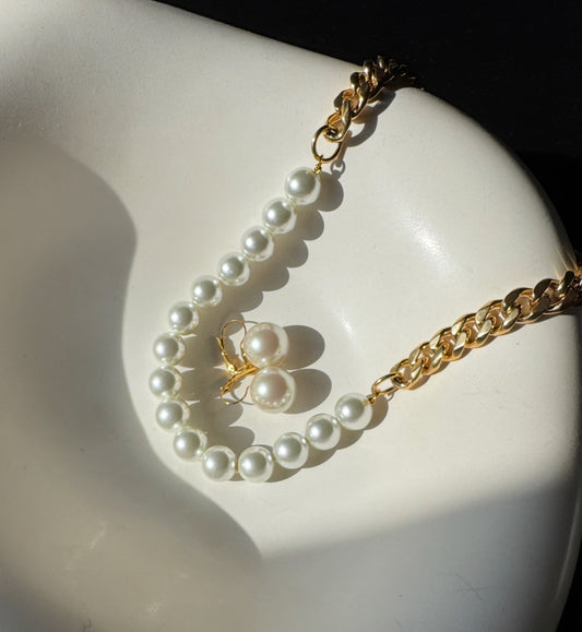 Pearl necklace and earrings on a white dish with a gold chain
