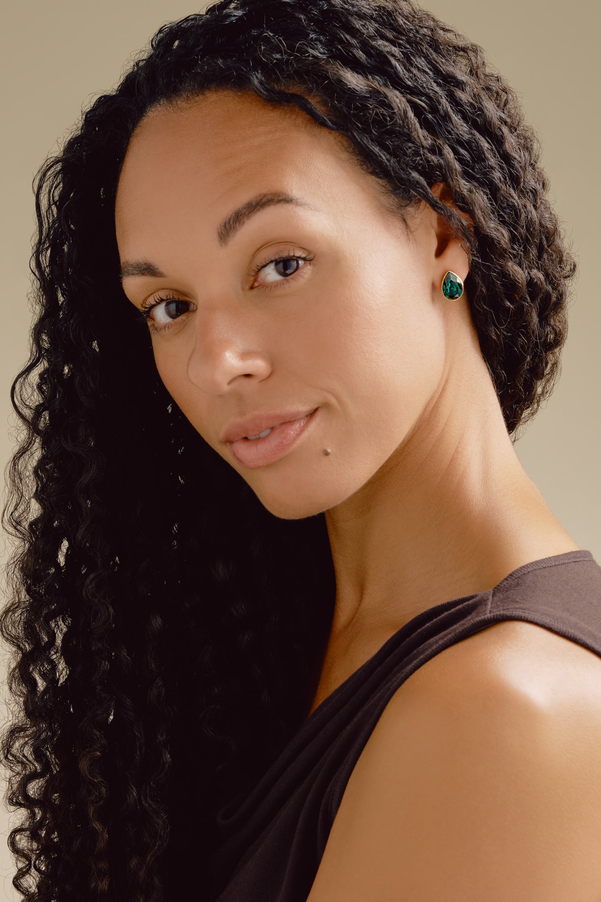Woman with styled hair and earrings against a neutral background