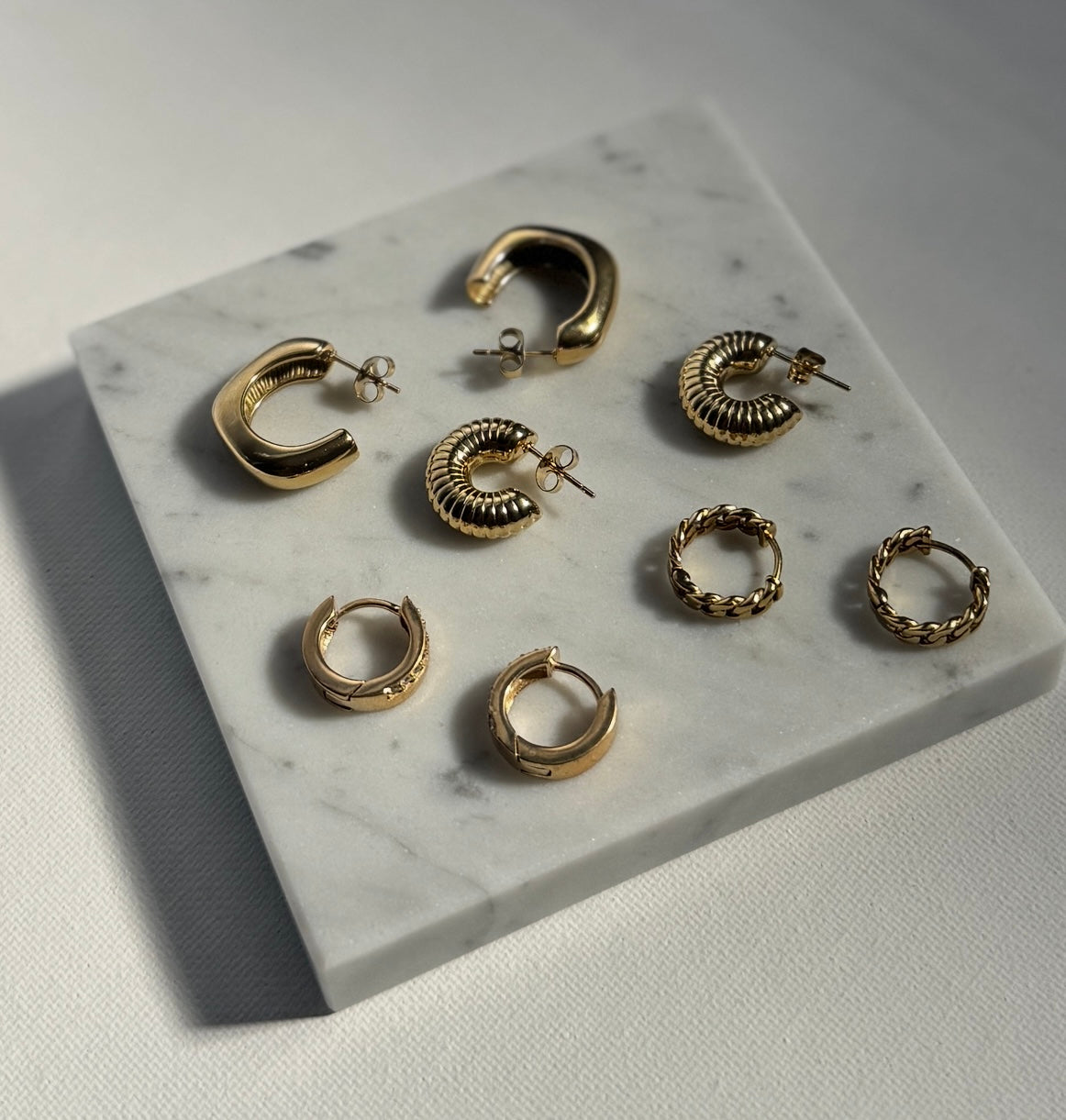 Gold hoop earrings displayed on a marble surface