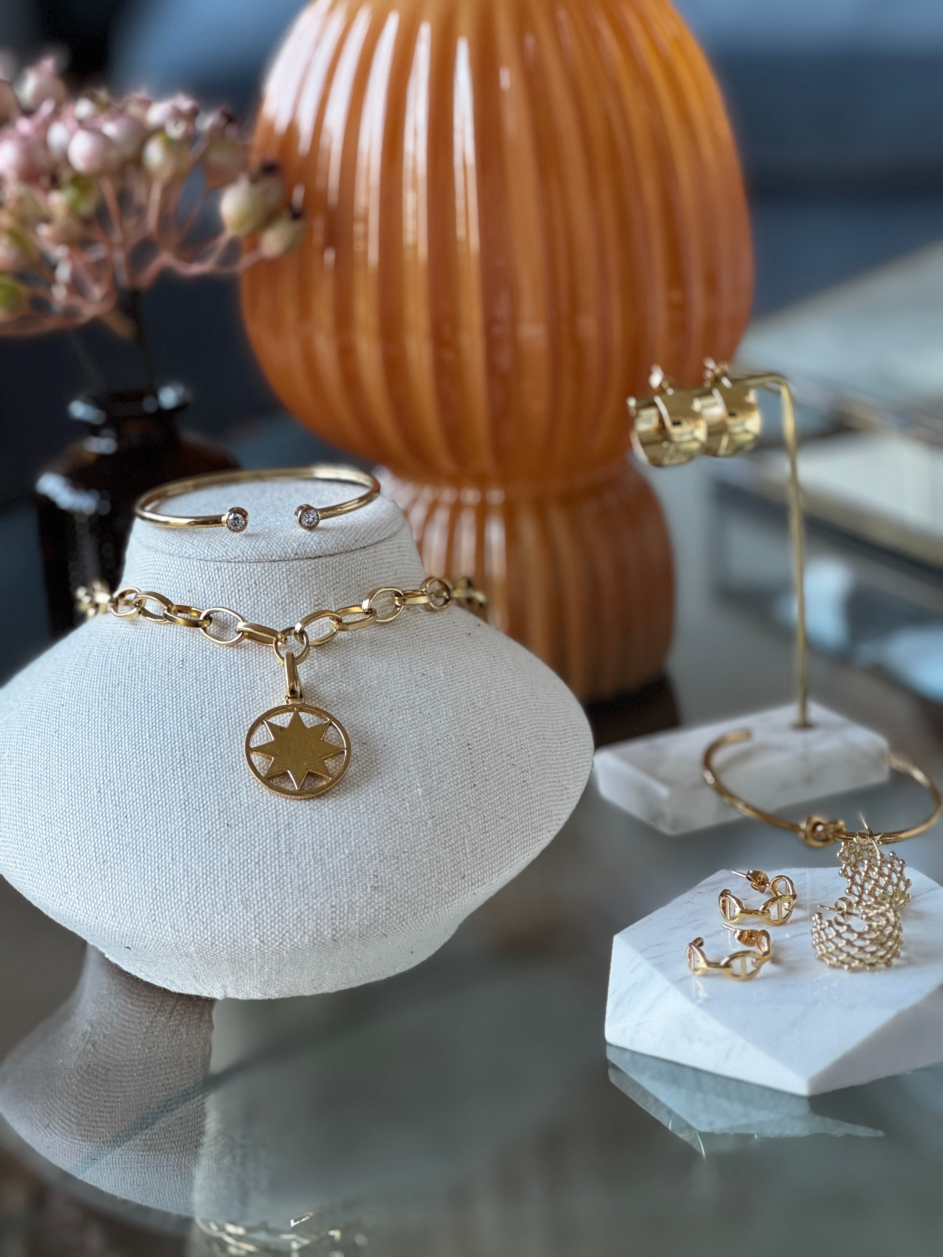 Gold jewellery including bracelets and rings on display stands with a blurred background
