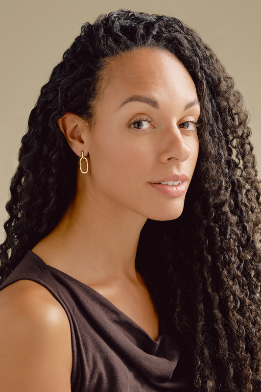 A model wearing gold bamboo hoop clip earrings