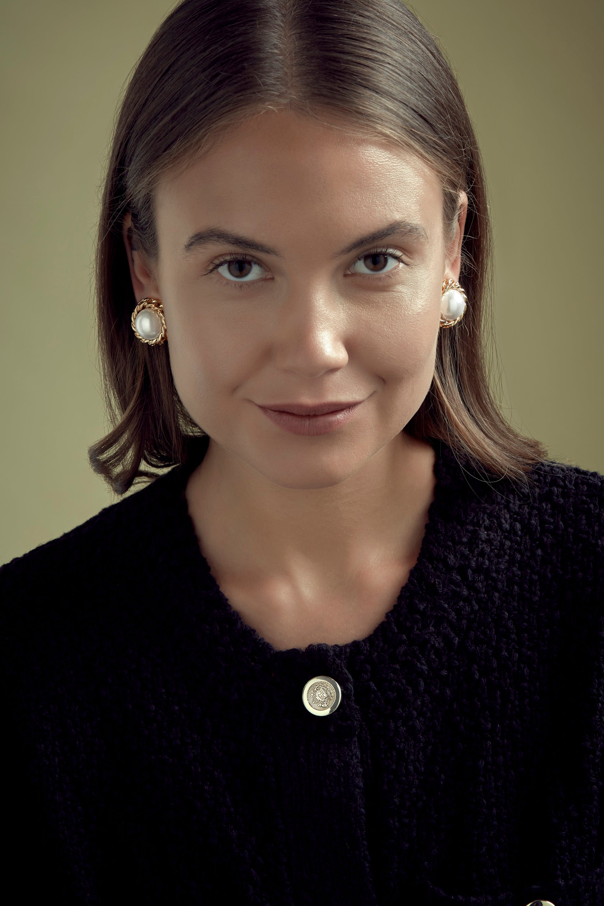 Model wearing large pearl and gold clip on earrings