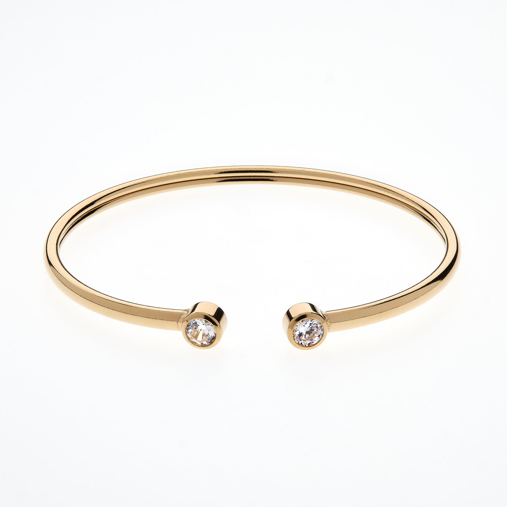 Gold bangle with two small diamonds on a white background