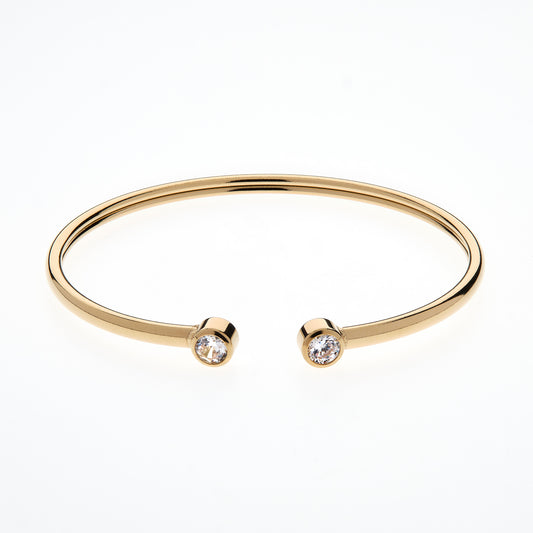 Gold bangle with two small diamonds on a white background