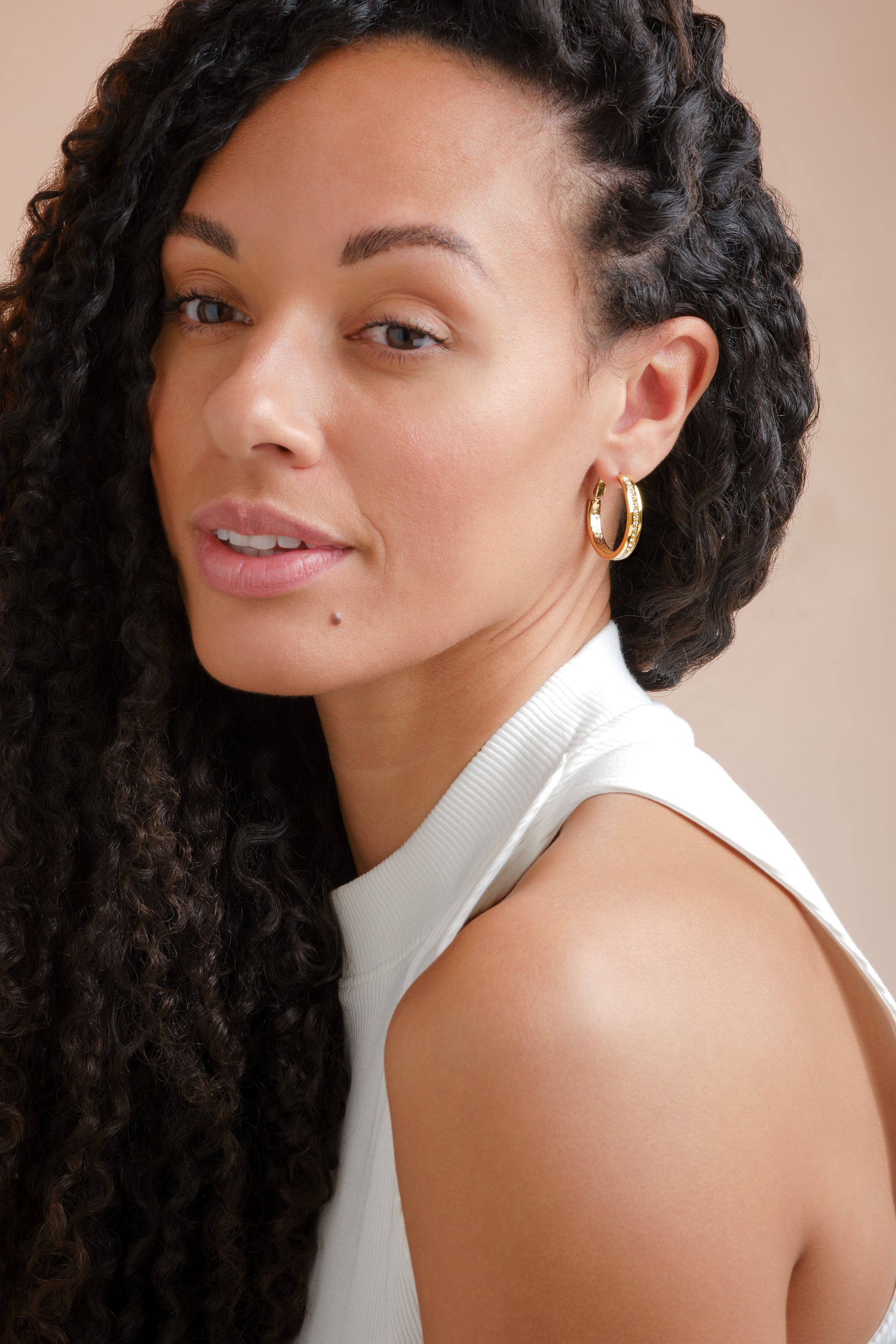A model with gold and crystal hoop earrings