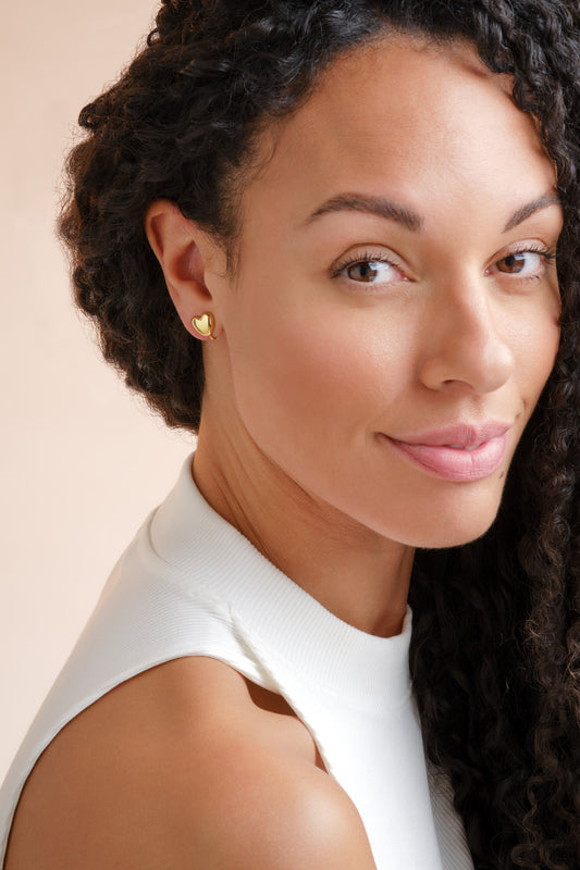A model wearing gold heart clip earrings