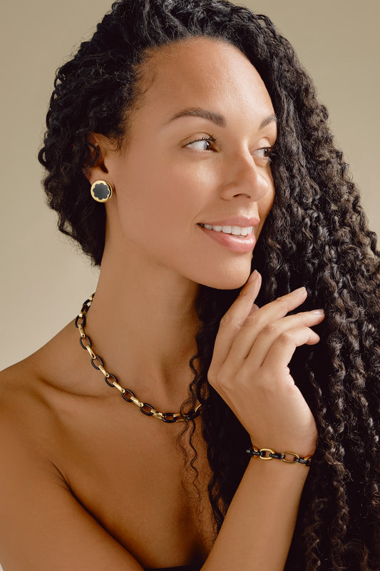 Woman with styled hair wearing jewelry against a neutral background