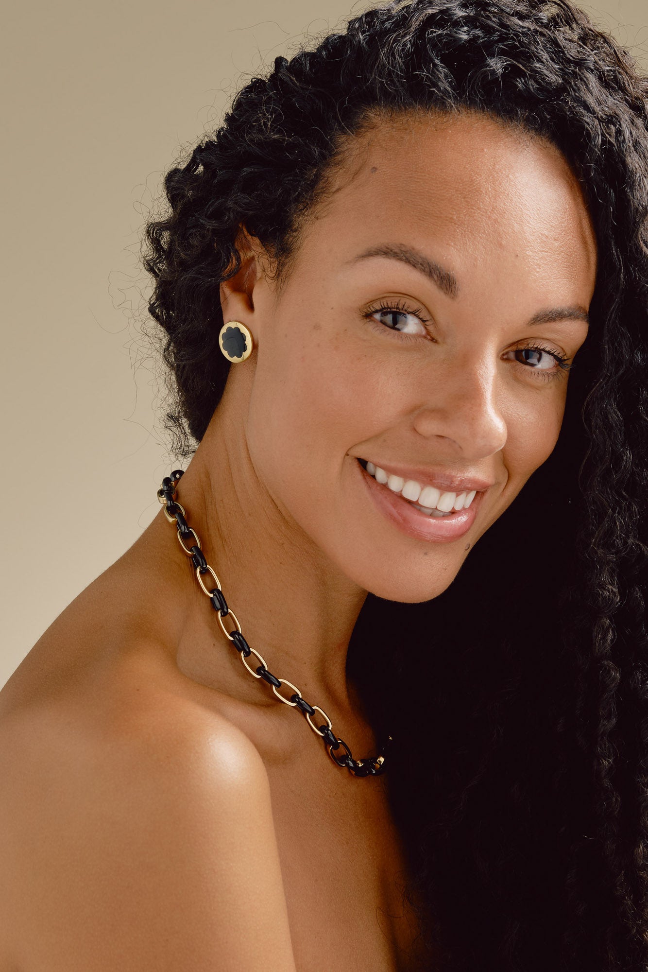 Woman with dark hair and a necklace against a neutral background