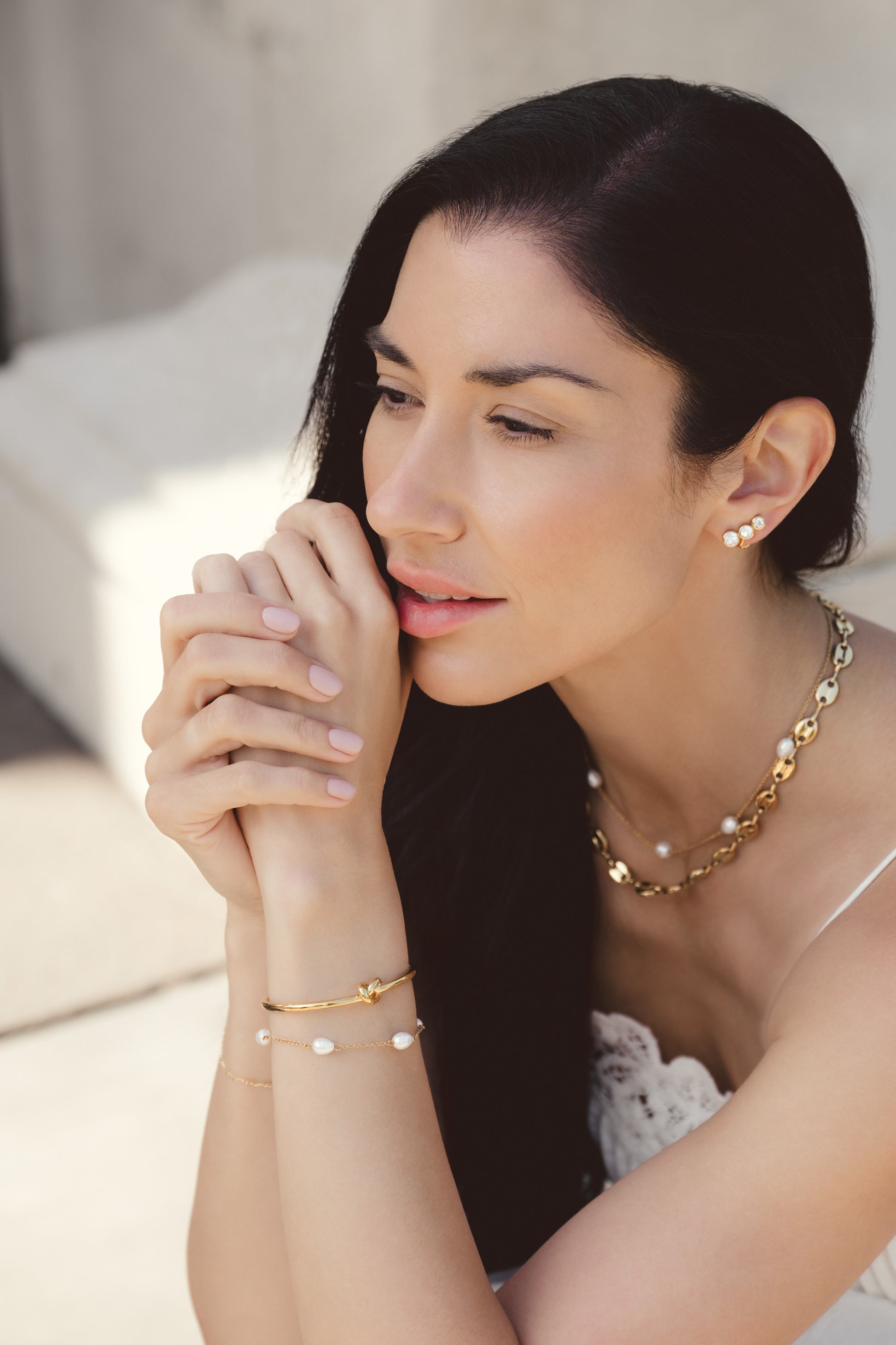 Woman wearing gold jewelry with a neutral background