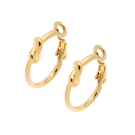 A pair of gold hoop clip on earrings with a knot design, displayed against a white background.