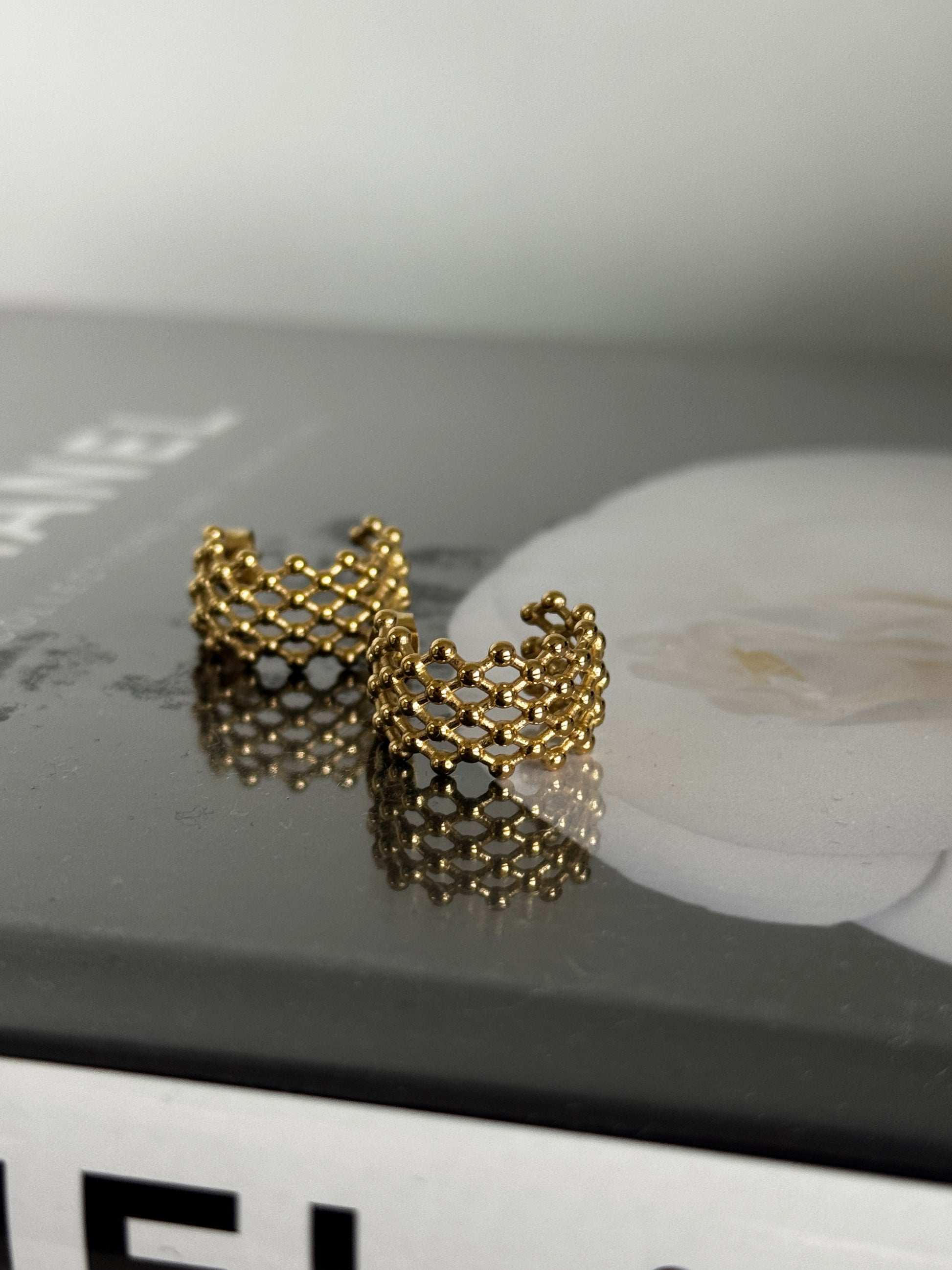 Gold chain-style earrings on a blurred background