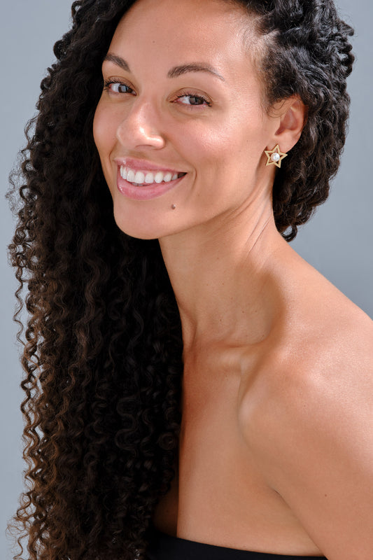 A model wearing gold star earrings with pearls