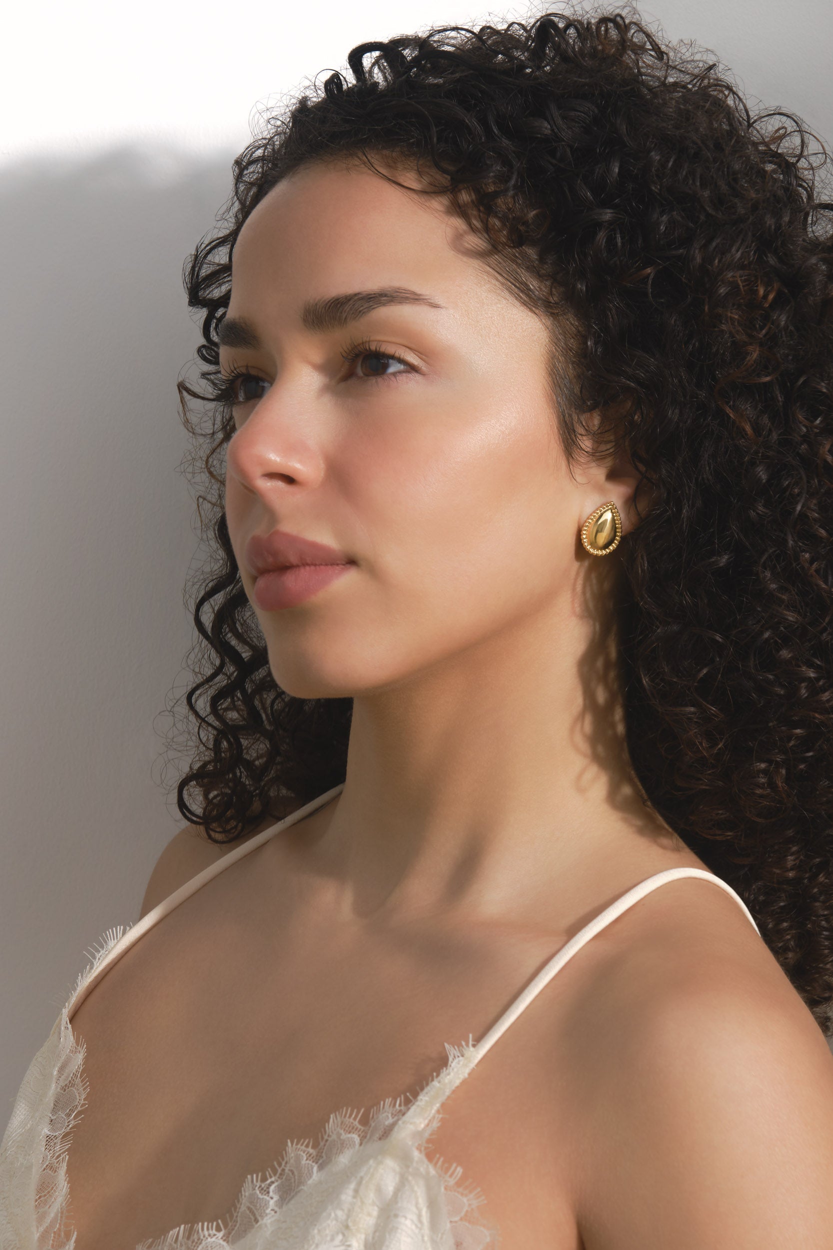 Woman wearing a gold earring with a neutral background