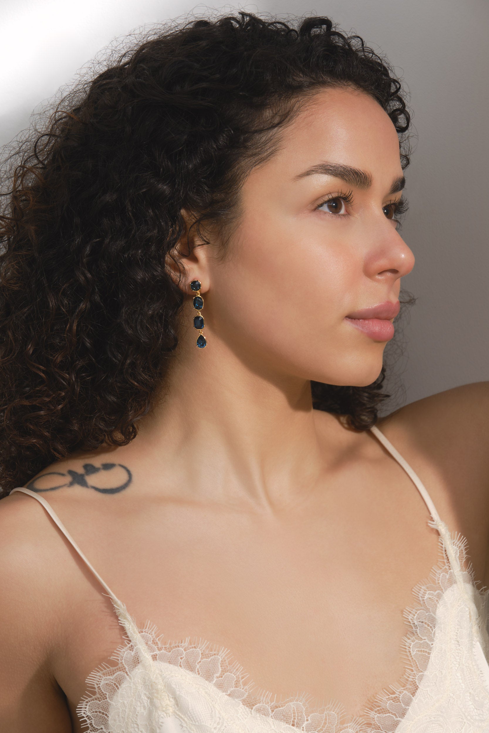 Woman wearing a white lace top with a neutral background