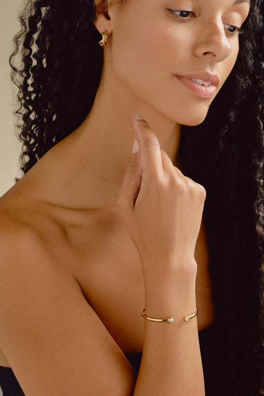 Woman wearing a gold bracelet with a neutral background