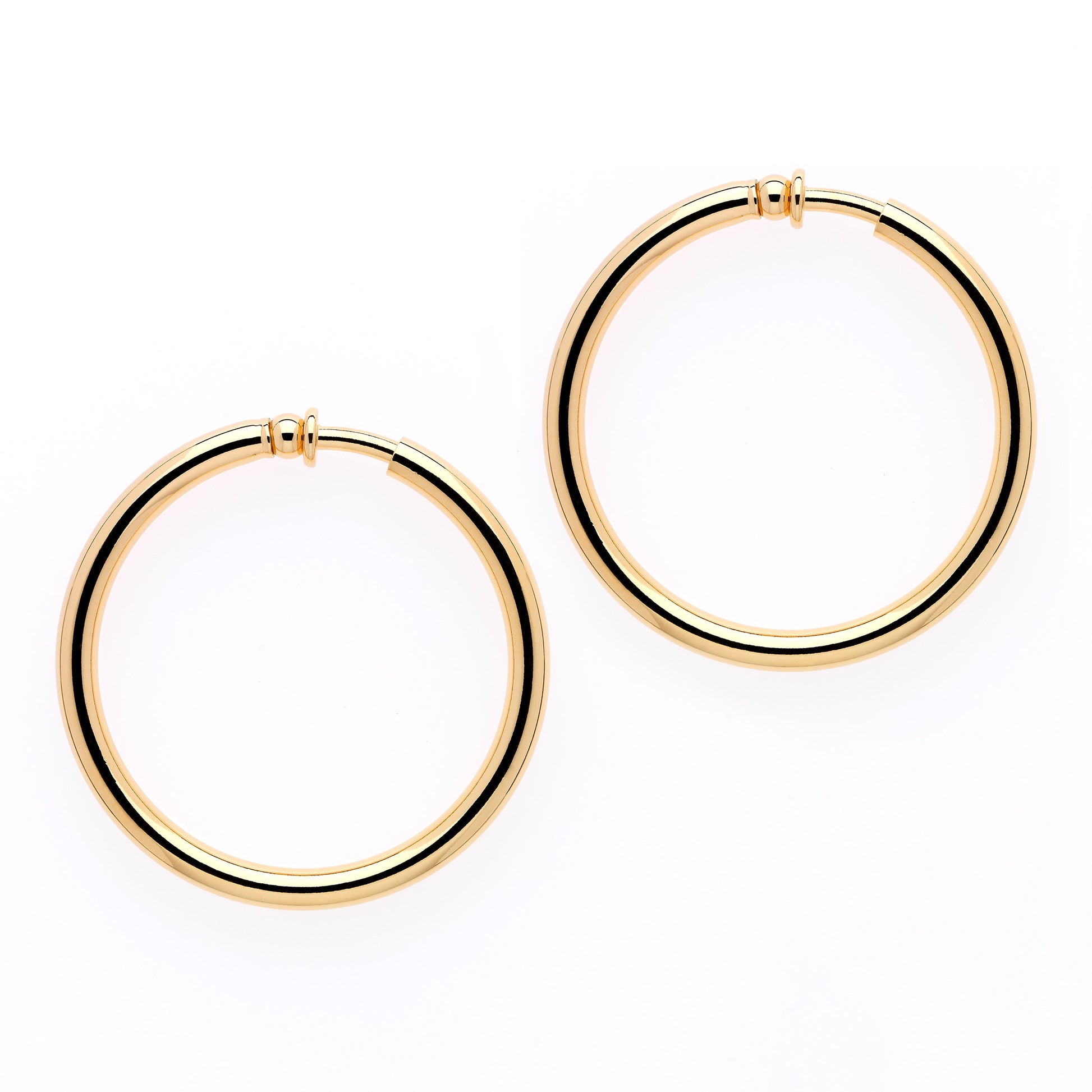 A pair of large gold hoop clip earrings on a white background.