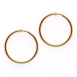 A pair of large gold hoop clip earrings on a white background.