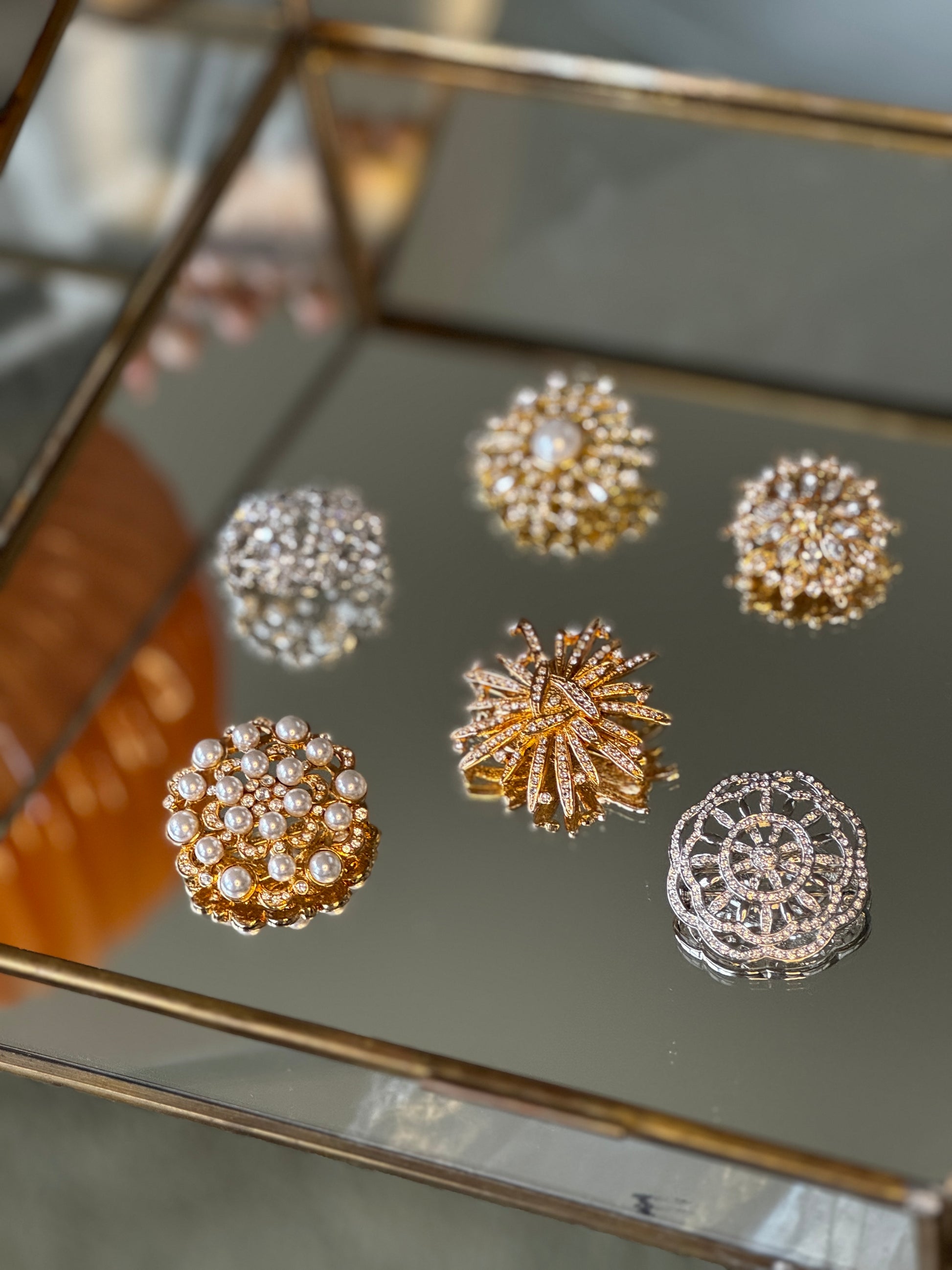 Set of gold and silver brooches on a reflective surface