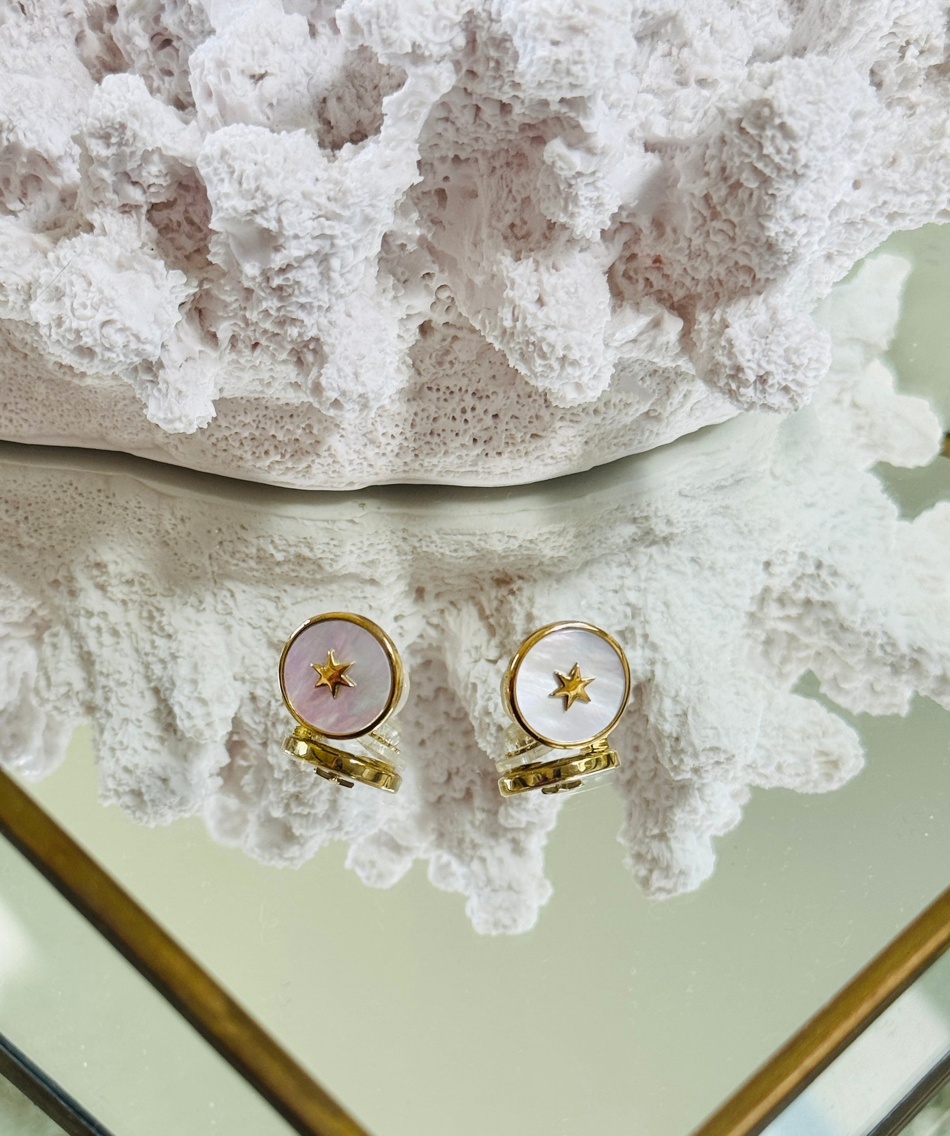 Gold rings with pink stones on a textured white surface
