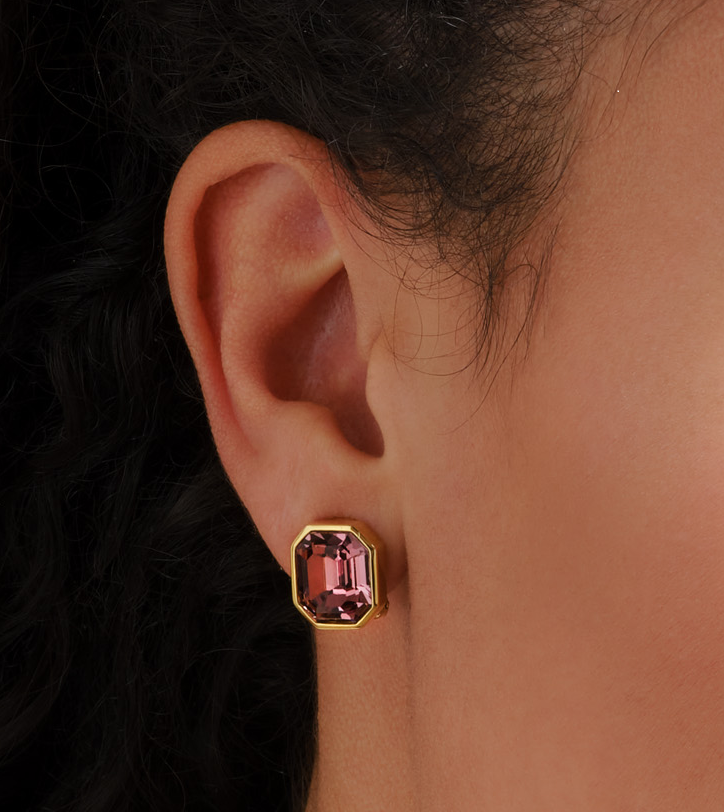 Gold earring with purple gemstone worn by a model