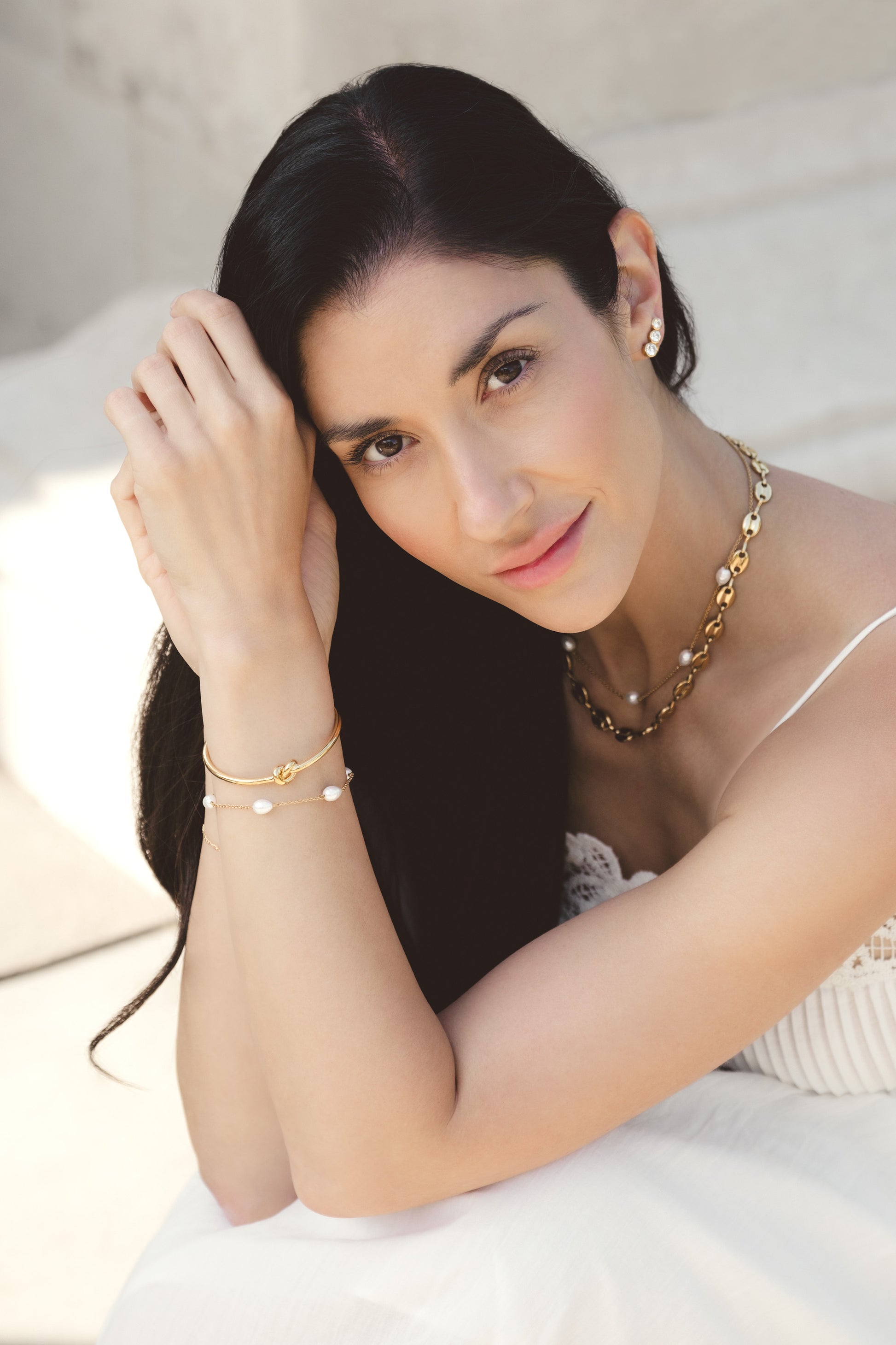 Woman wearing gold jewelry including a necklace, bracelet, and earrings.