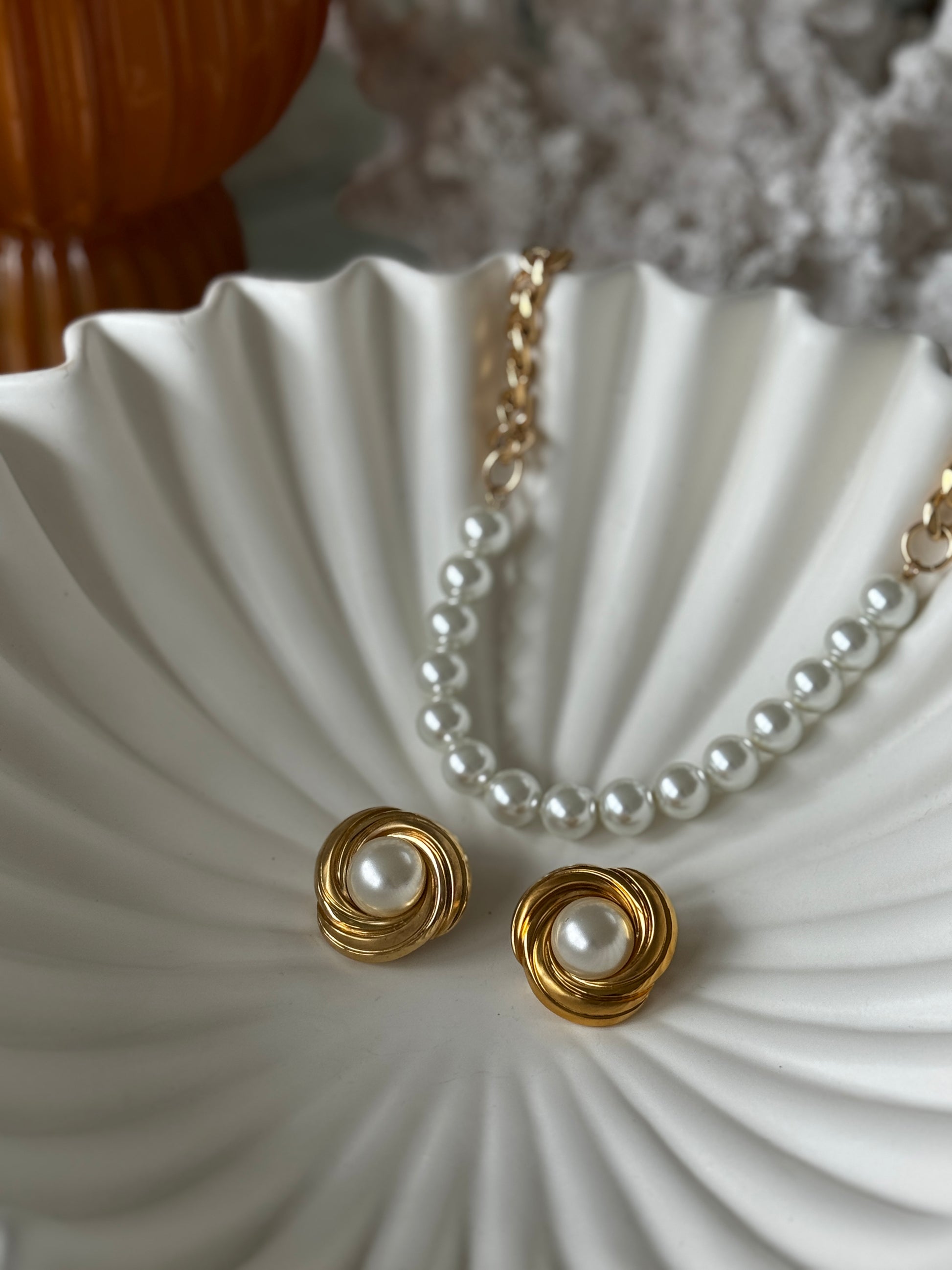 Pearl necklace and earrings on a white shell